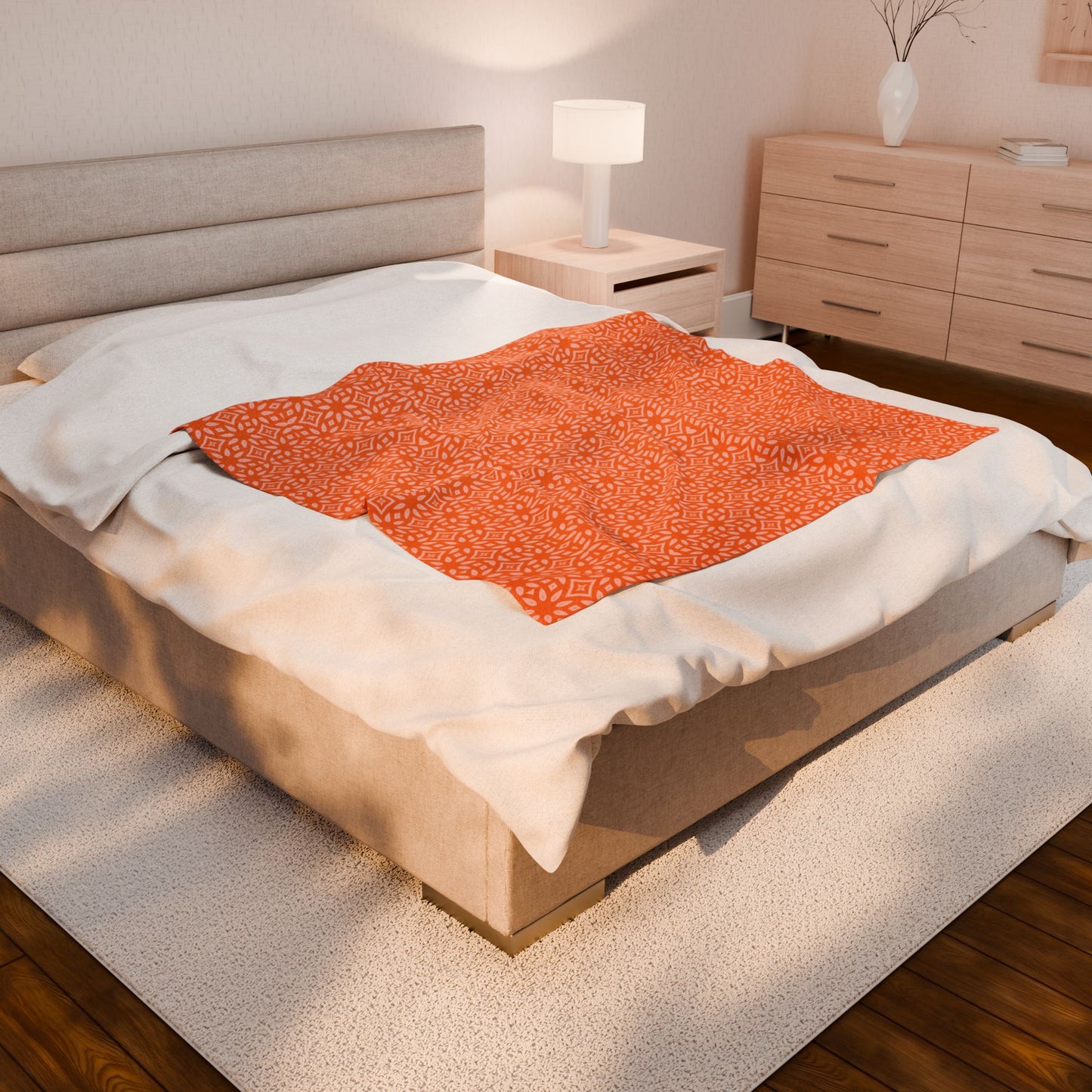Bed with orange patterned blanket and beige pillows in a bedroom setting.