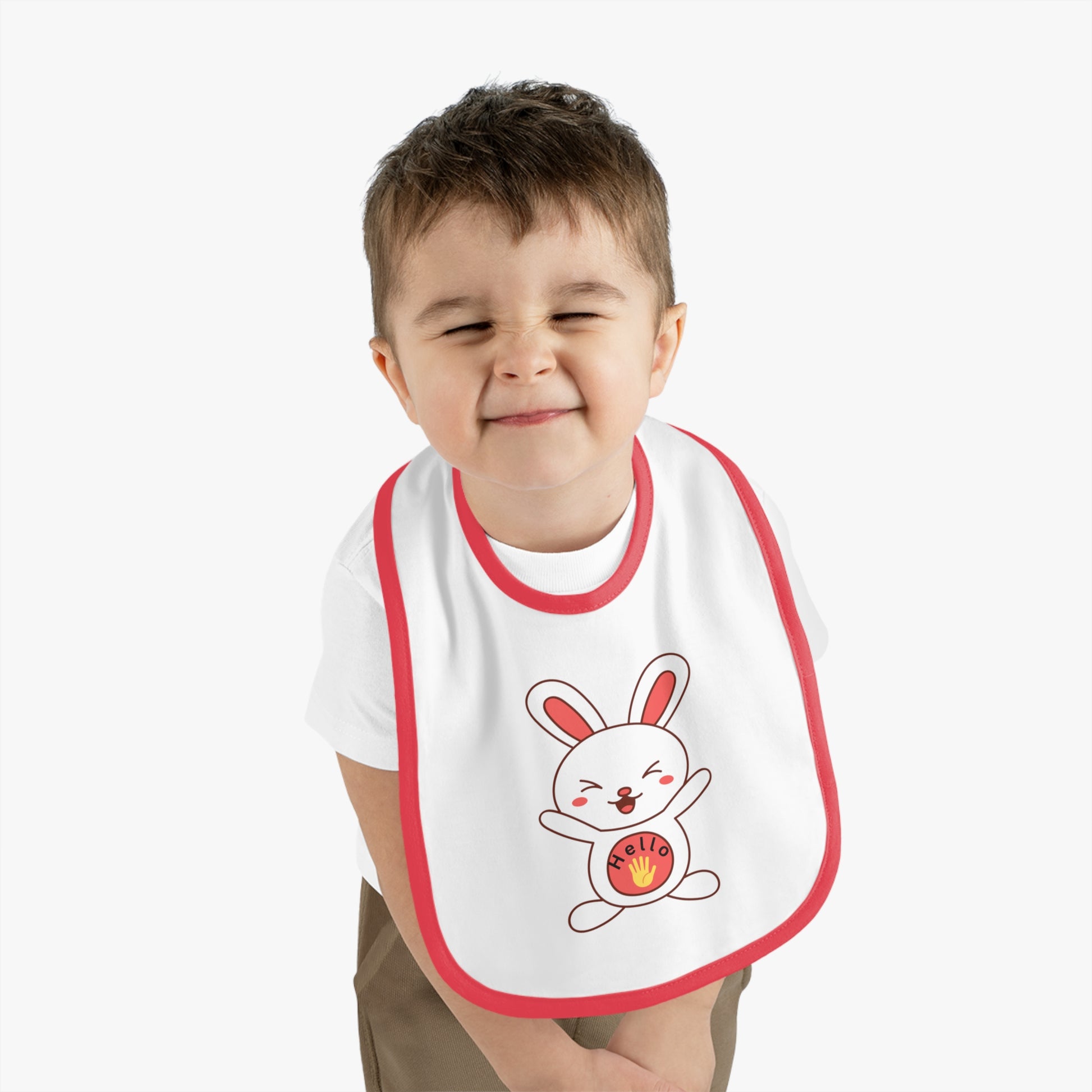 Child wearing a white bib with a cartoon rabbit and red border on a plain background