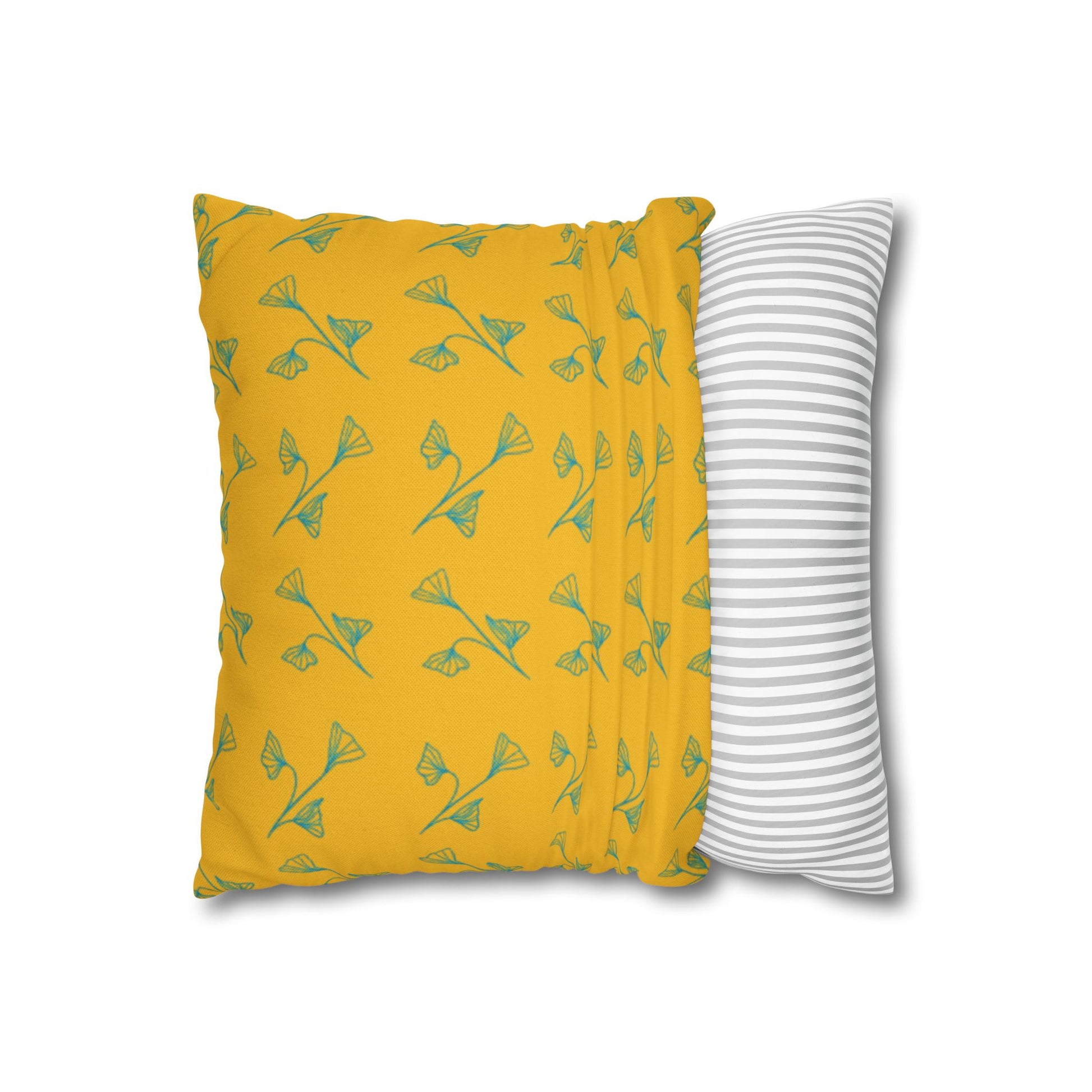 Yellow pillow with green leaf pattern and gray and white striped pillow on white background