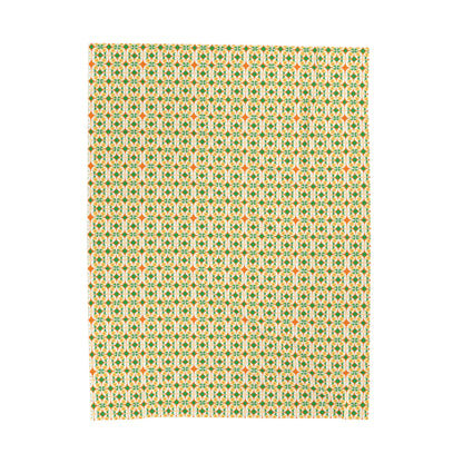 A folded velveteen plush blanket with a geometric pattern in green, yellow, and red colors.