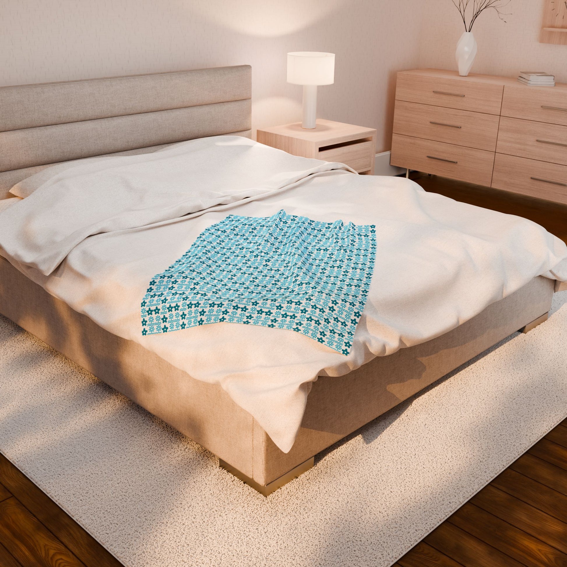 Bed with a blue patterned blanket in a bedroom setting