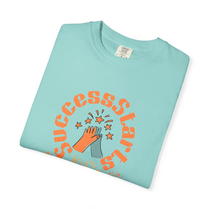 Folded light blue t-shirt with orange text and graphic on a white background