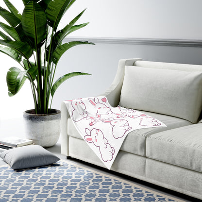 Sofa in a living room with a cartoon blanket and a potted plant.