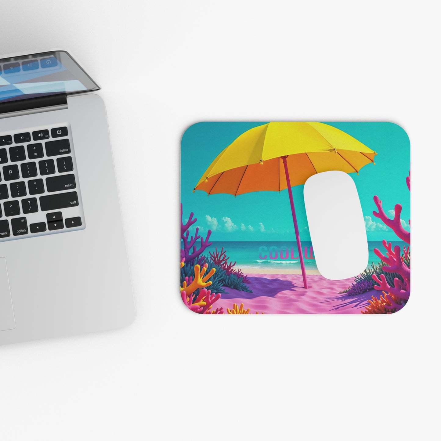 Mouse pad with tropical design next to a laptop on a white surface.
