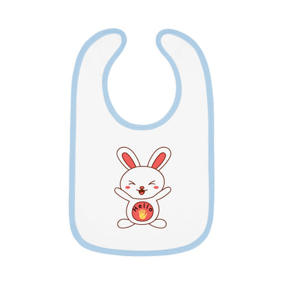 A white baby bib with  blue contrast trim and a centered graphic of a smiling cartoon rabbit holding a round object.