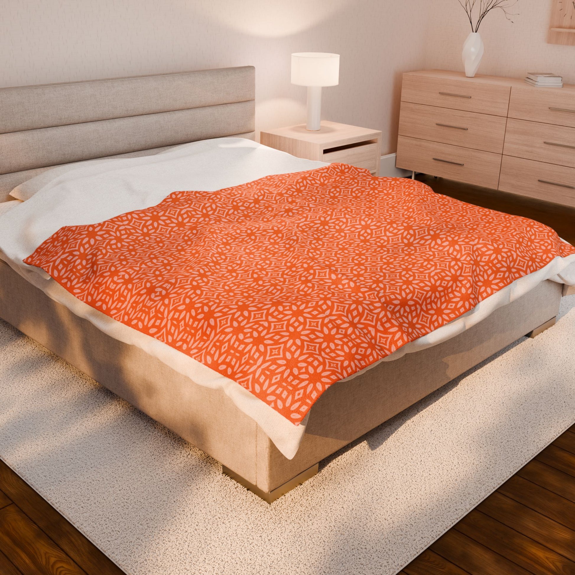 Bed with orange patterned blanket in a bedroom setting