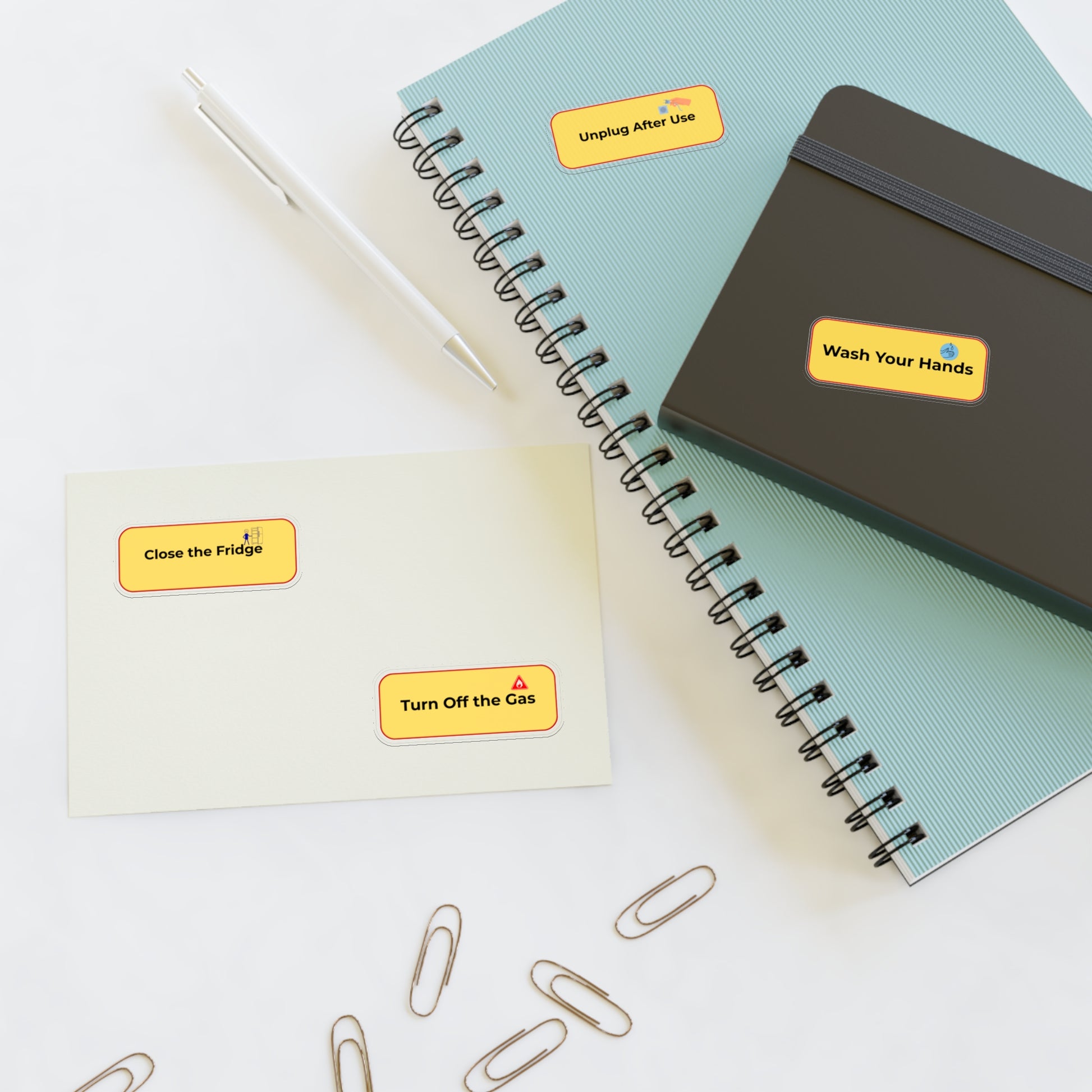 Notebooks with safety labels and paper clips on a white surface