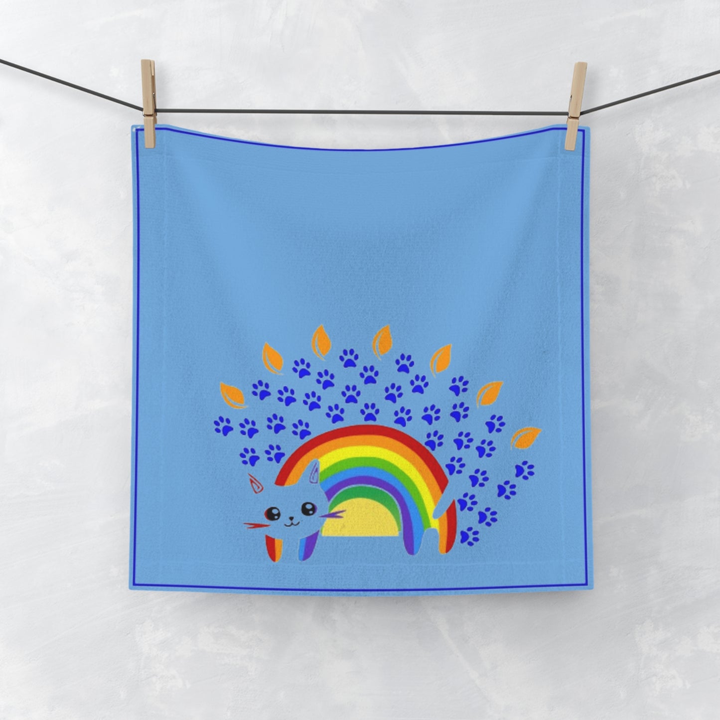 Blue towel with a rainbow and paw prints design hanging on a line.
