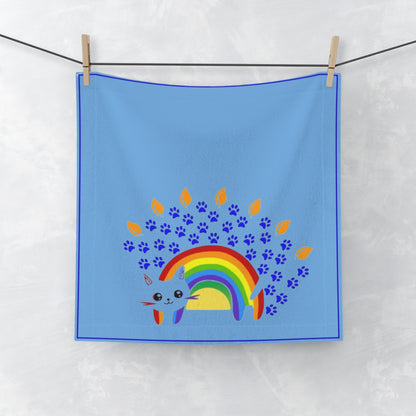 Blue towel with a rainbow and paw prints design hanging on a line.