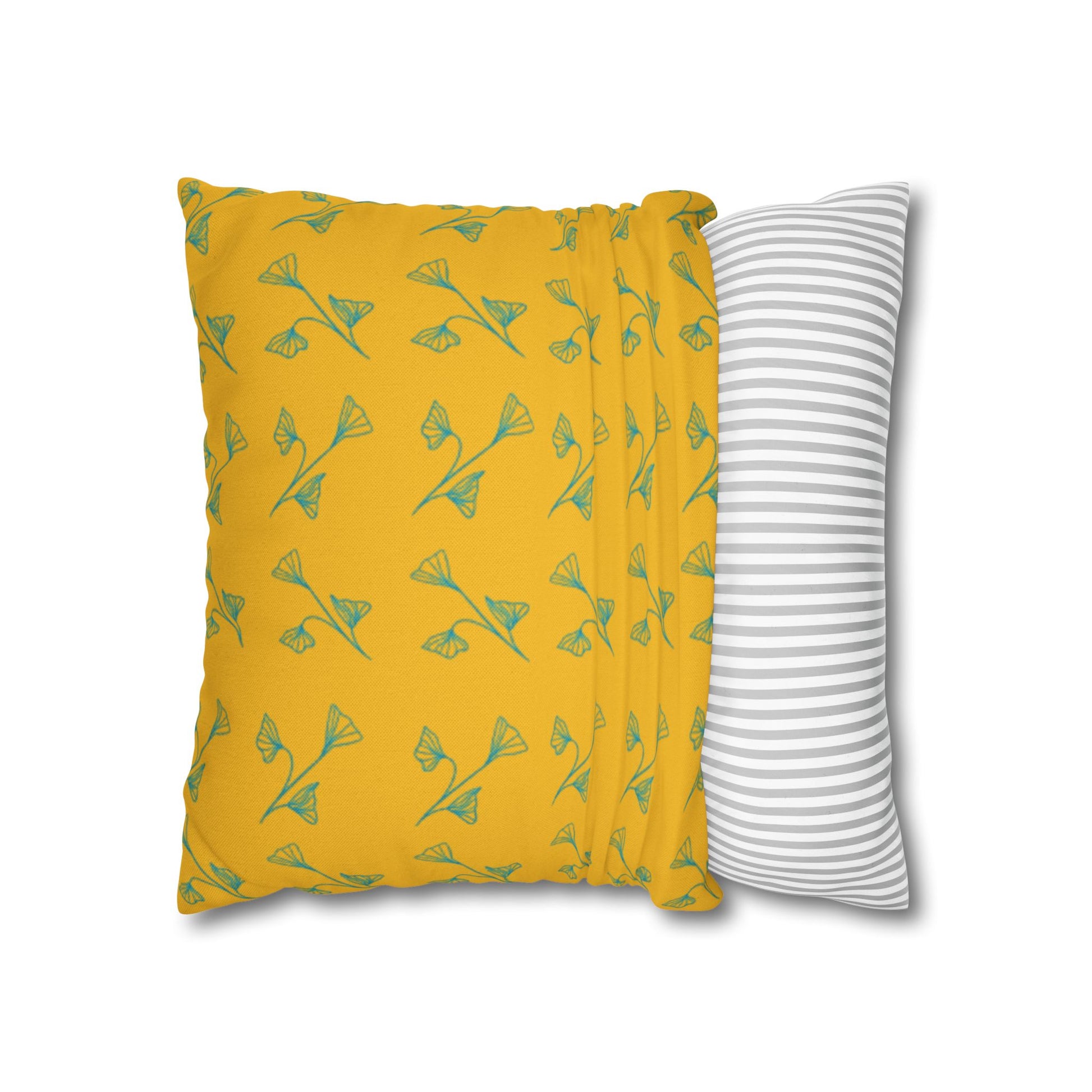 Yellow pillow with green leaf pattern and gray and white striped pillow on white background