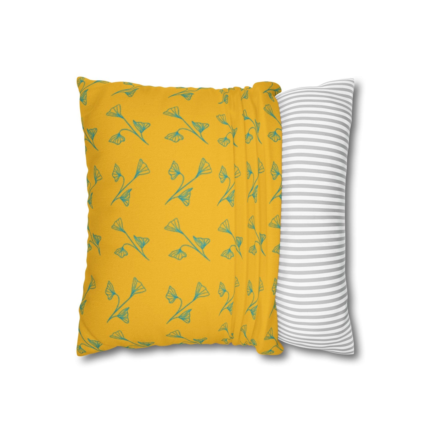 Yellow pillow with green leaf pattern and gray and white striped pillow on white background