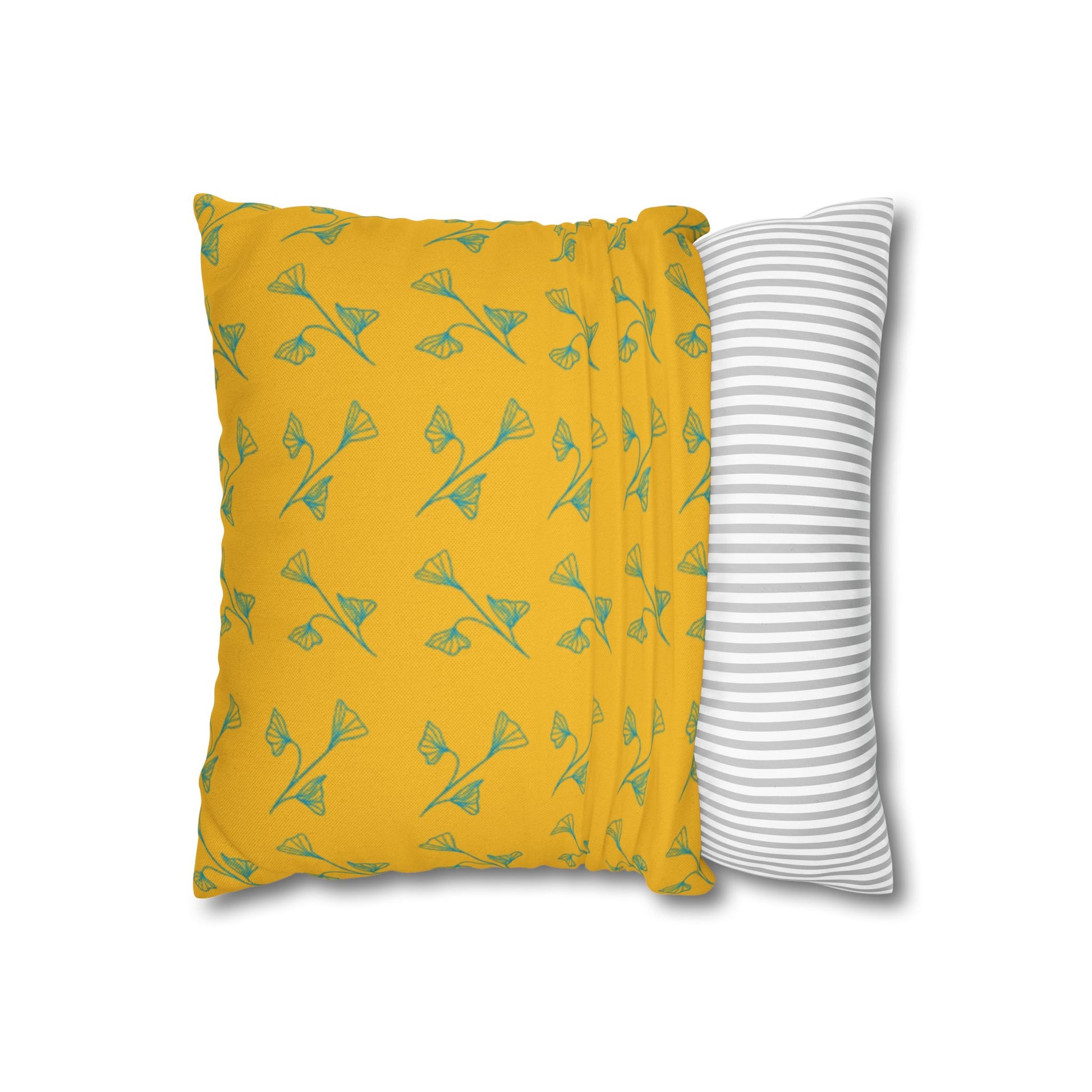 Yellow pillow with green leaf pattern and gray and white striped pillow on white background
