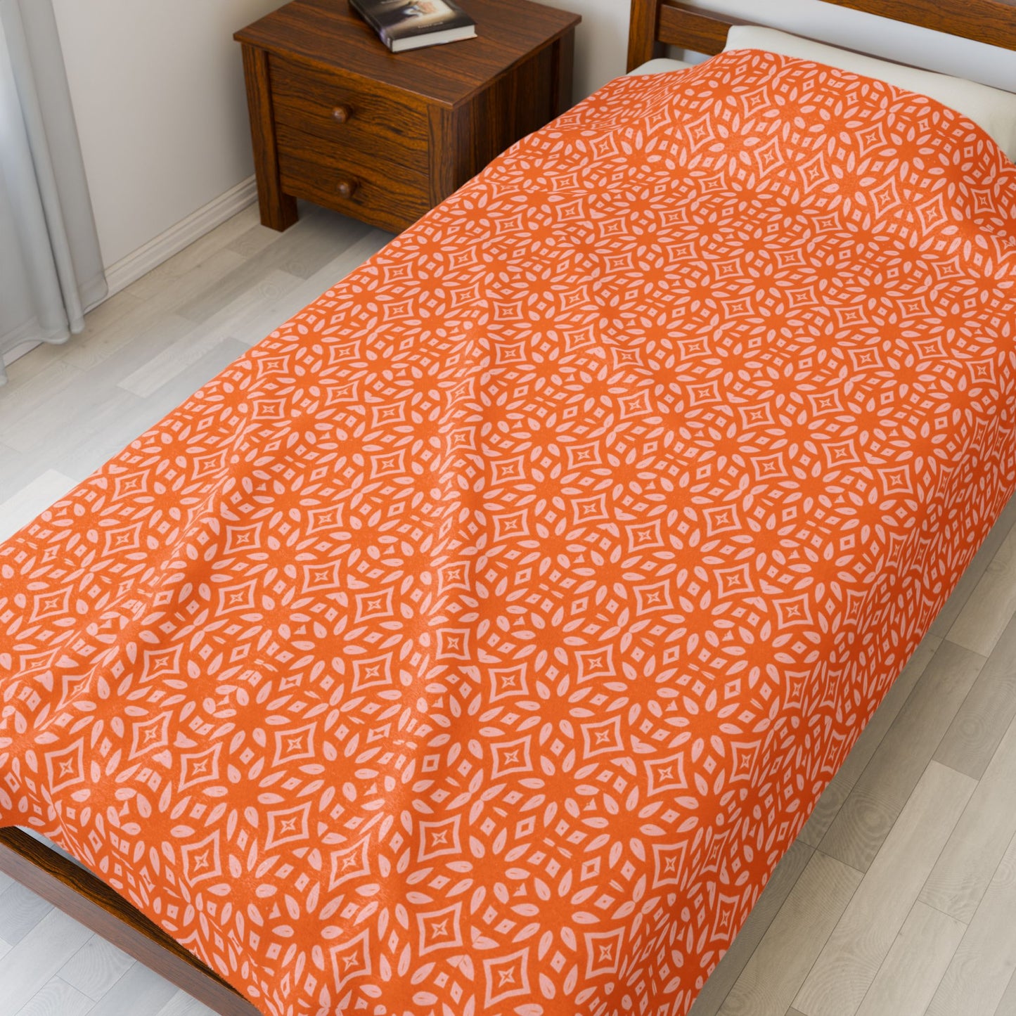 Bed with orange patterned bedspread in a bedroom.