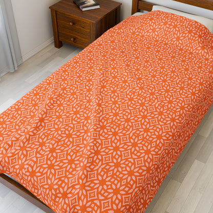 Bed with orange patterned bedspread in a bedroom.