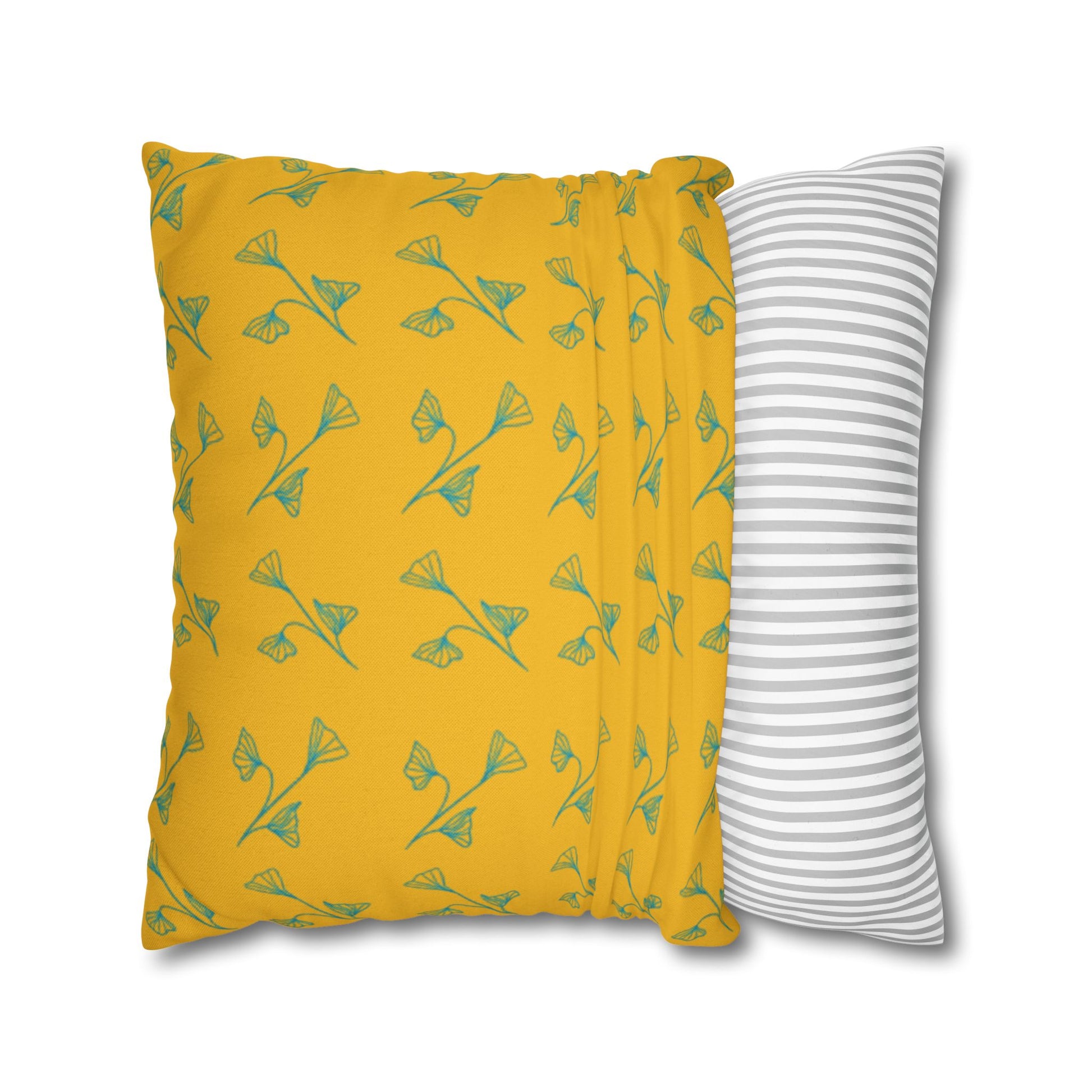 Yellow pillow with green leaf pattern and gray and white striped pillow on white background