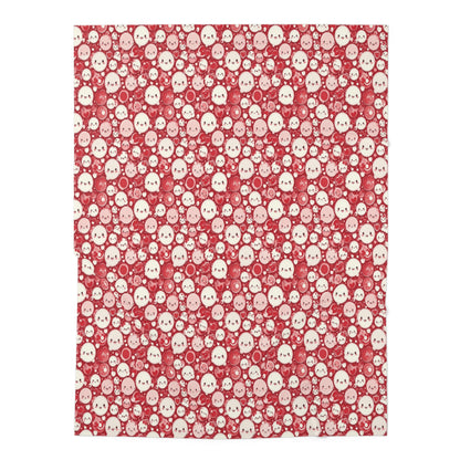 A red and white baby swaddle blanket with a pattern of cute faces.
