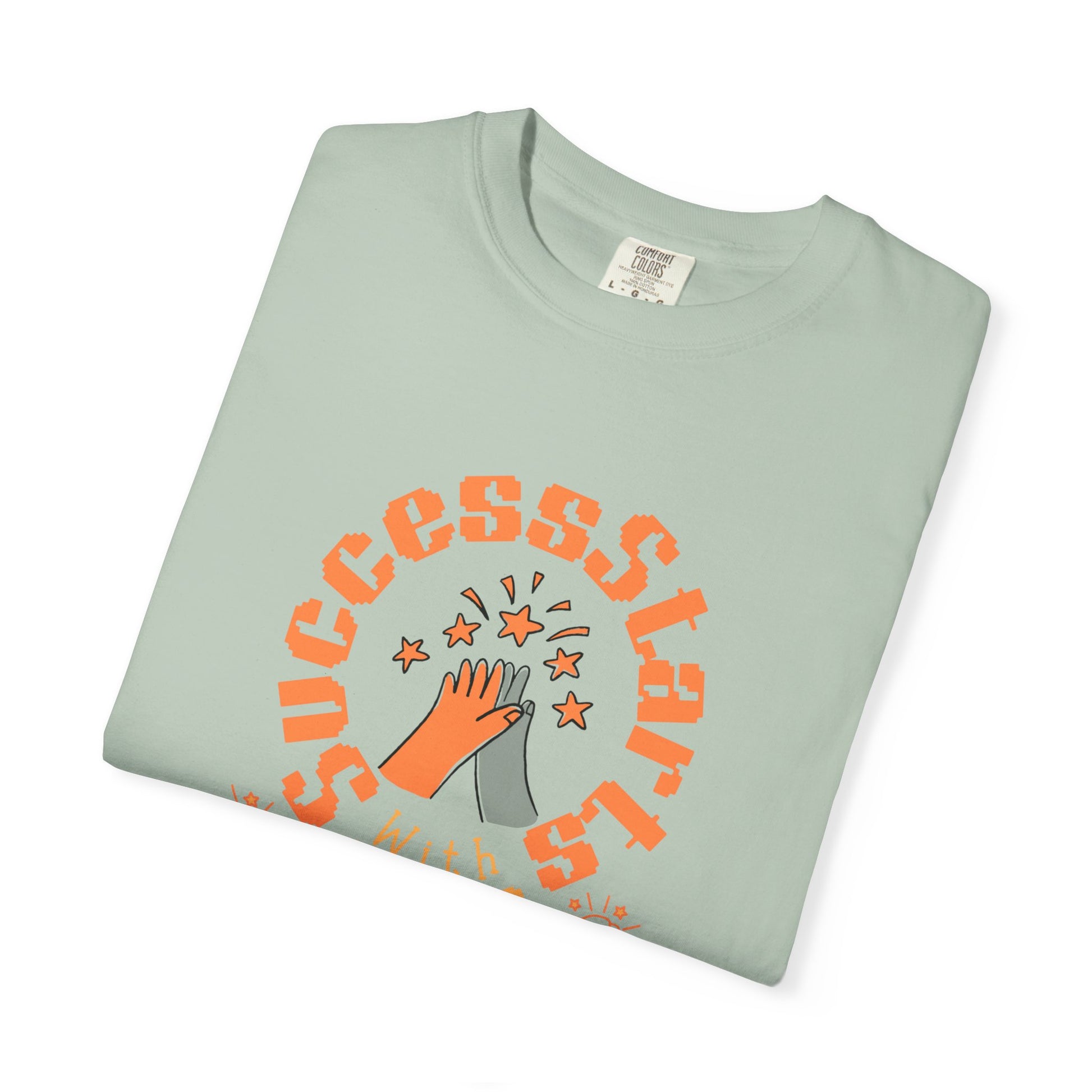 Folded light green t-shirt with orange 'SUCCESS STARS' design on a white background