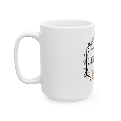 A white ceramic coffee mug with a handle, featuring a partially visible black and purple gothic-style graphic on the side.