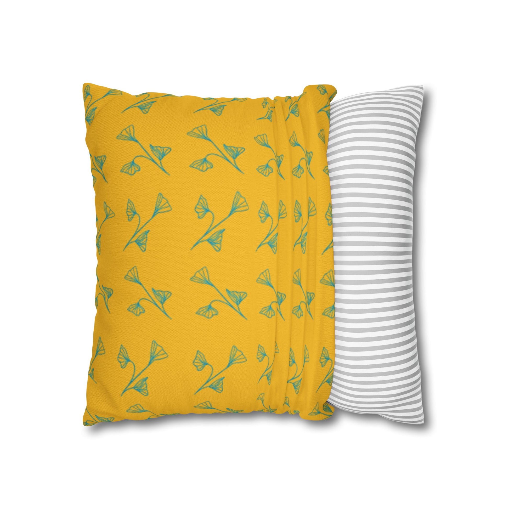 Yellow pillow with green leaf pattern and gray and white striped pillow on white background