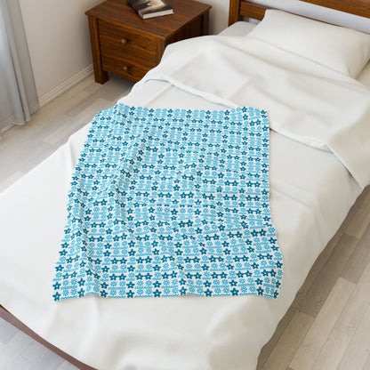 Blue patterned blanket on a bed in a bedroom.