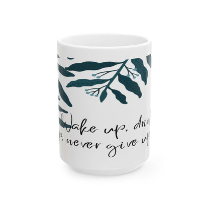 White ceramic mug with green leaf patterns and text that reads 'Wake up, and drink , never give up'.