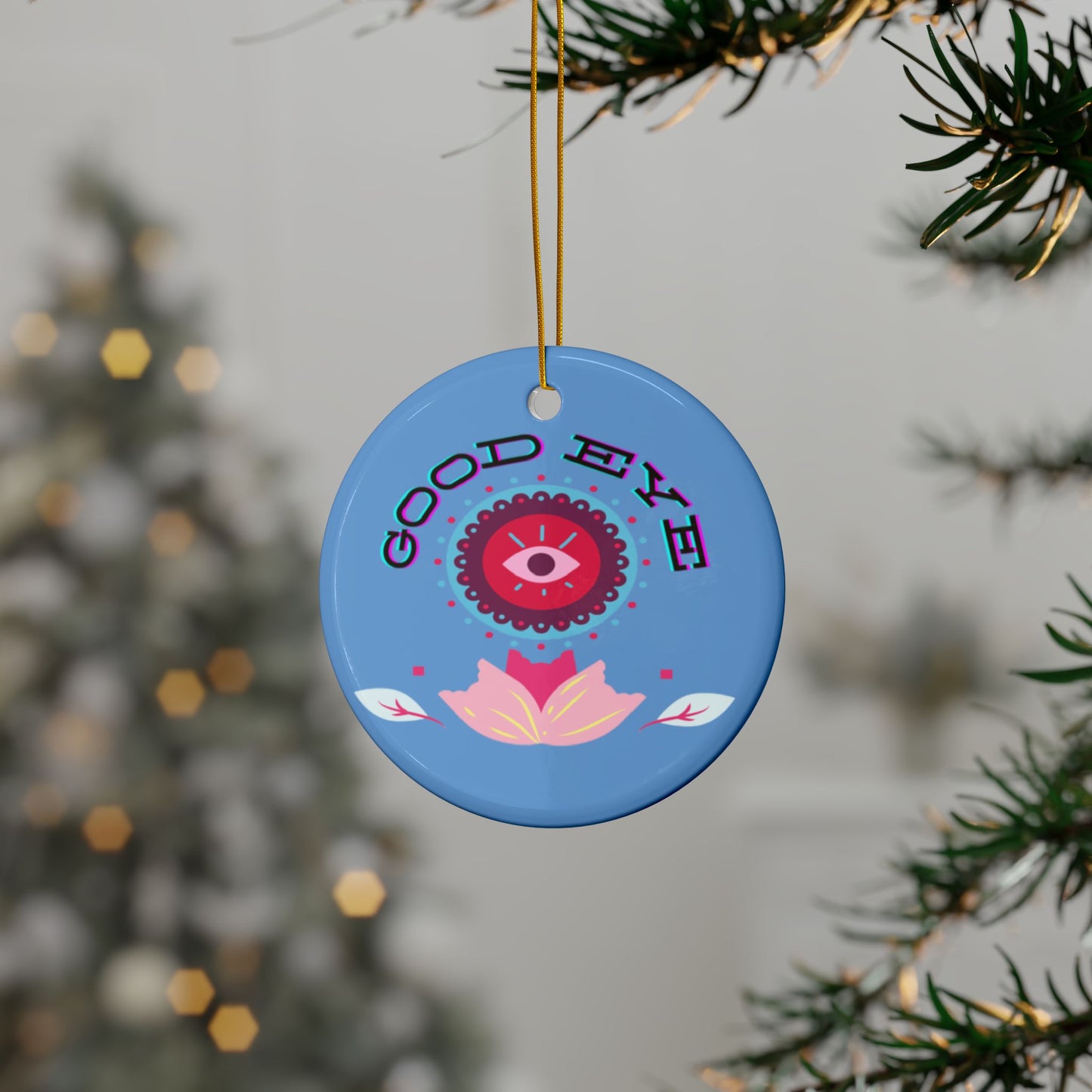 Blue decorative ornament with 'Good Eye' text and eye design hanging from a tree.