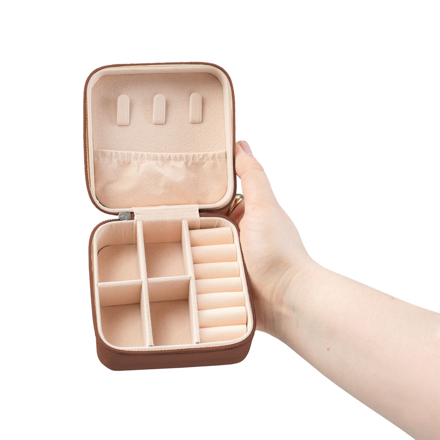 Hand holding a beige jewelry case with compartments on a white background