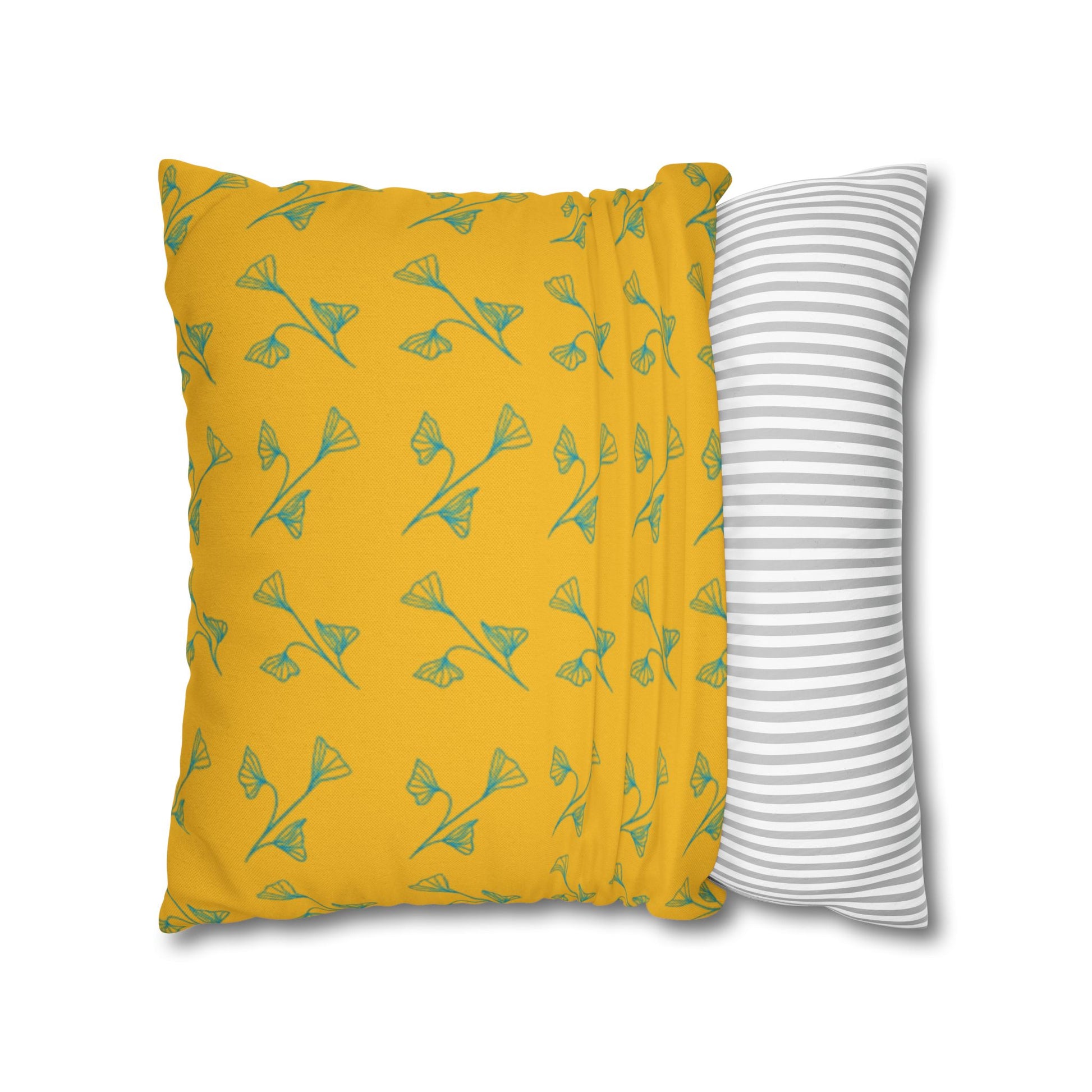 Yellow pillow with green leaf pattern and gray and white striped pillow on white background