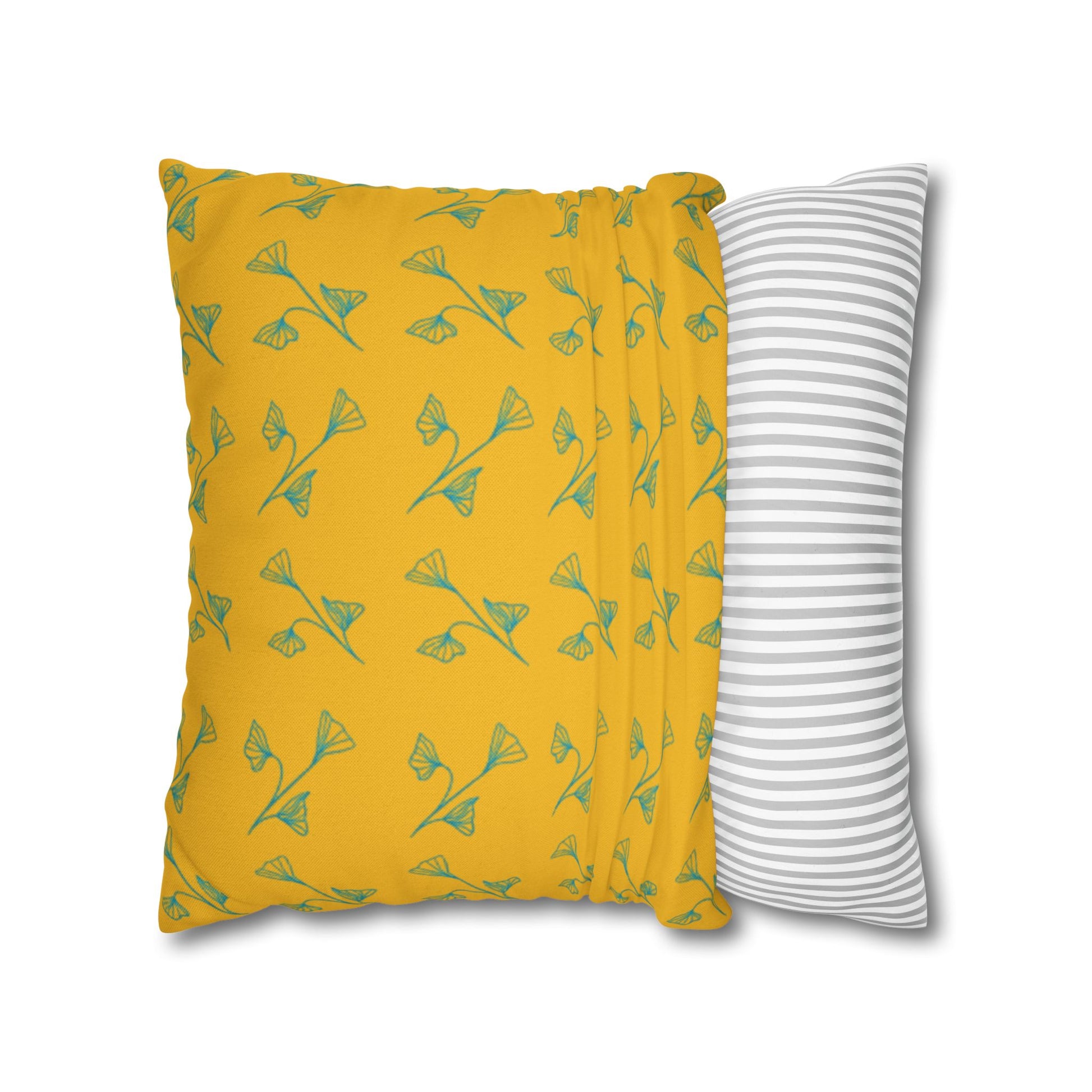 Yellow pillow with green leaf pattern and gray and white striped pillow on white background