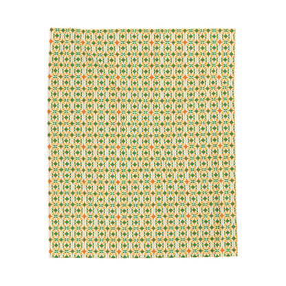 A folded velveteen plush blanket with a geometric pattern in green, yellow, and red colors.