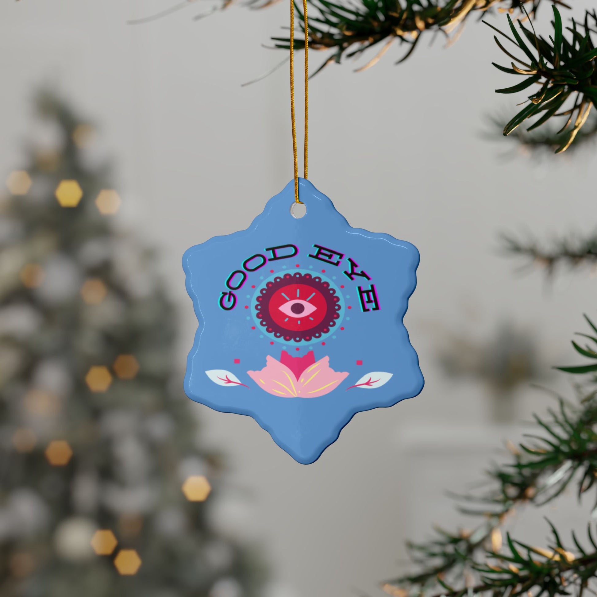 Blue decorative ornament with pink and red designs hanging from a tree
