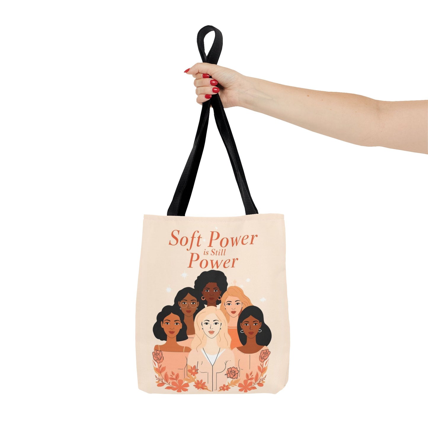 Tote bag with illustration of diverse women and text 'Soft Power is Still Power' held by a hand.