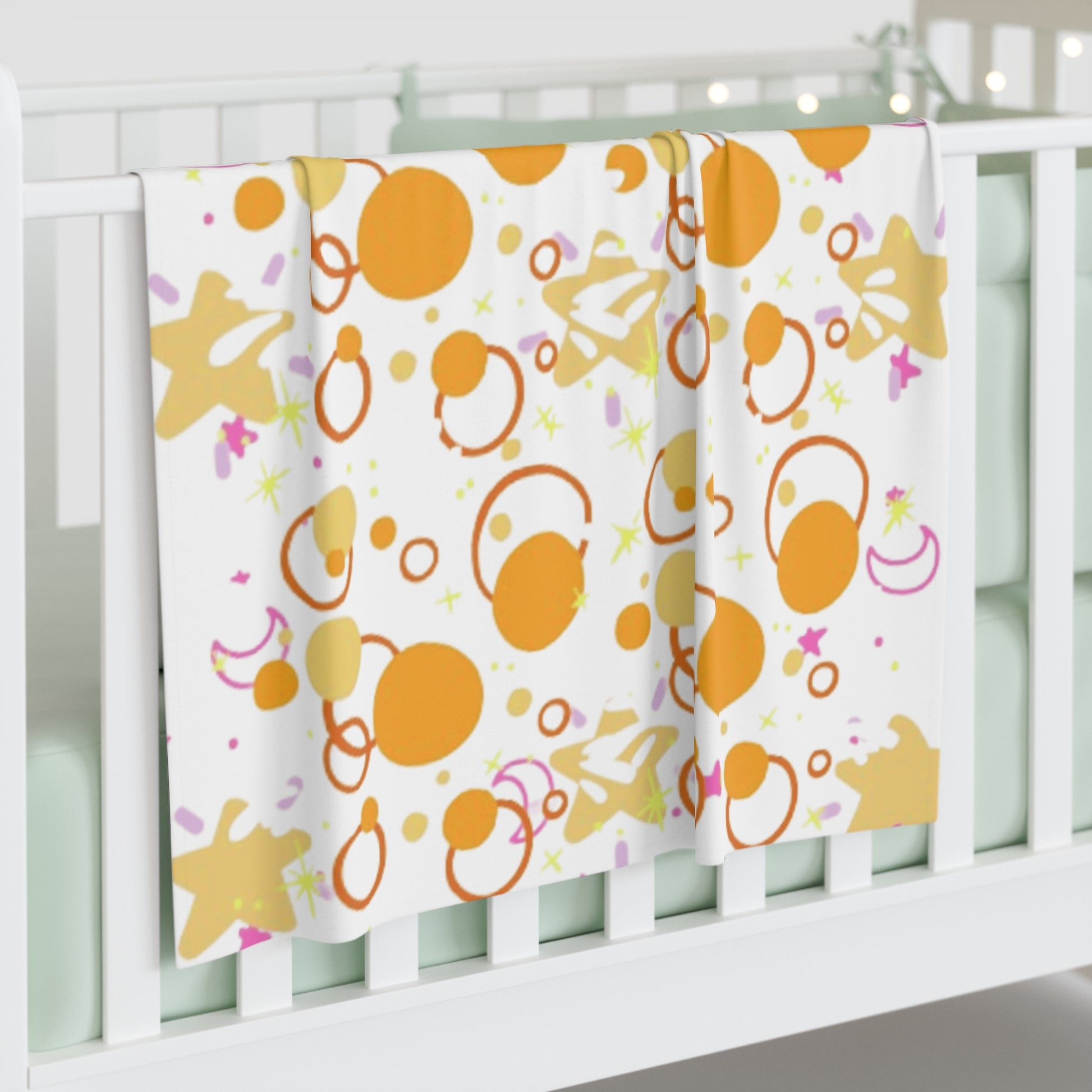 Baby crib with colorful patterned blanket featuring orange circles and pink stars.