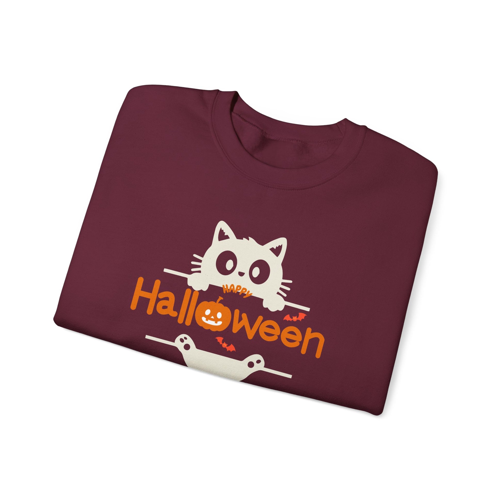 A folded maroon crewneck t-shirt featuring a 'Happy Halloween' graphic with a white cat, orange text, and a jack-o'-lantern, displayed on a clean white background.