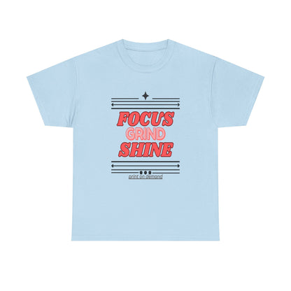 A light blue unisex heavy cotton tee with the text 'FOCUS GRIND SHINE' printed on the front.