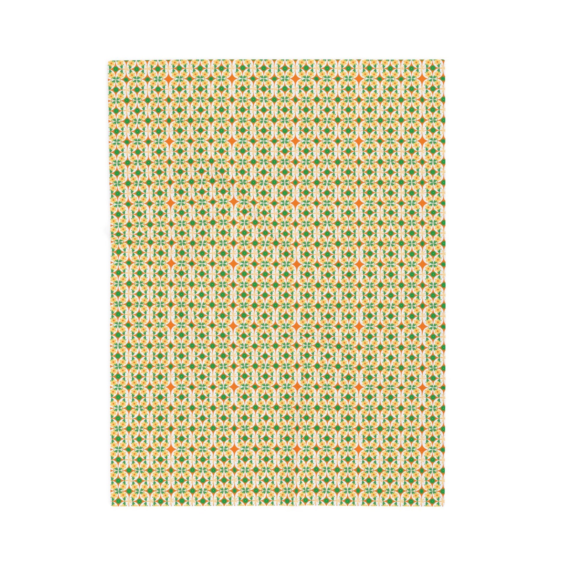 A folded velveteen plush blanket with a geometric pattern in green, yellow, and red colors.