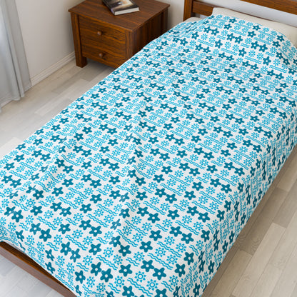 Bed with blue and white patterned bedspread in a bedroom.