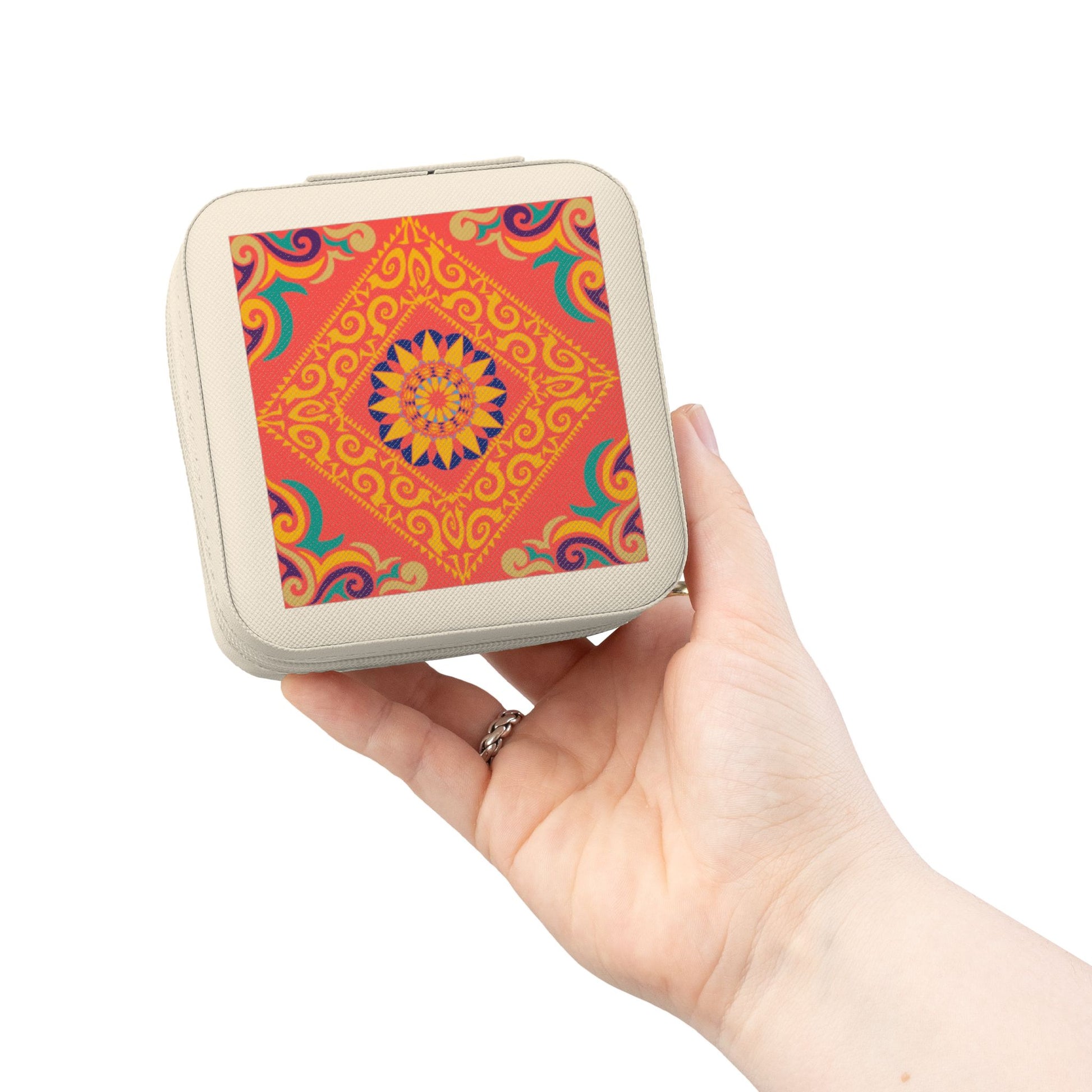 Hand holding a small square travel jewelry case with a colorful pattern on a white background