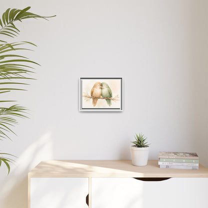 Framed artwork of two birds on a branch above a desk with a plant and books.