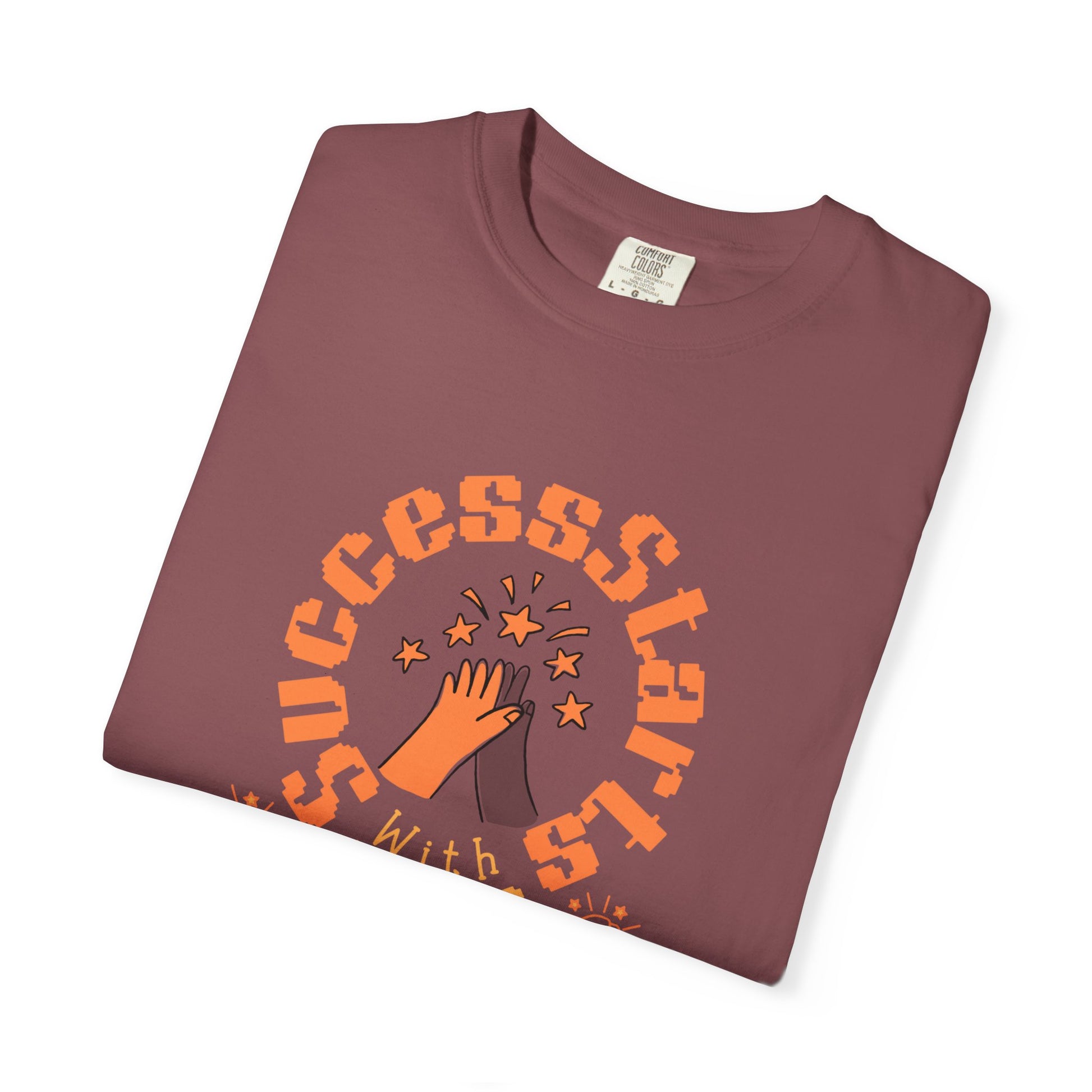 Folded maroon t-shirt with orange graphic and text on a white background