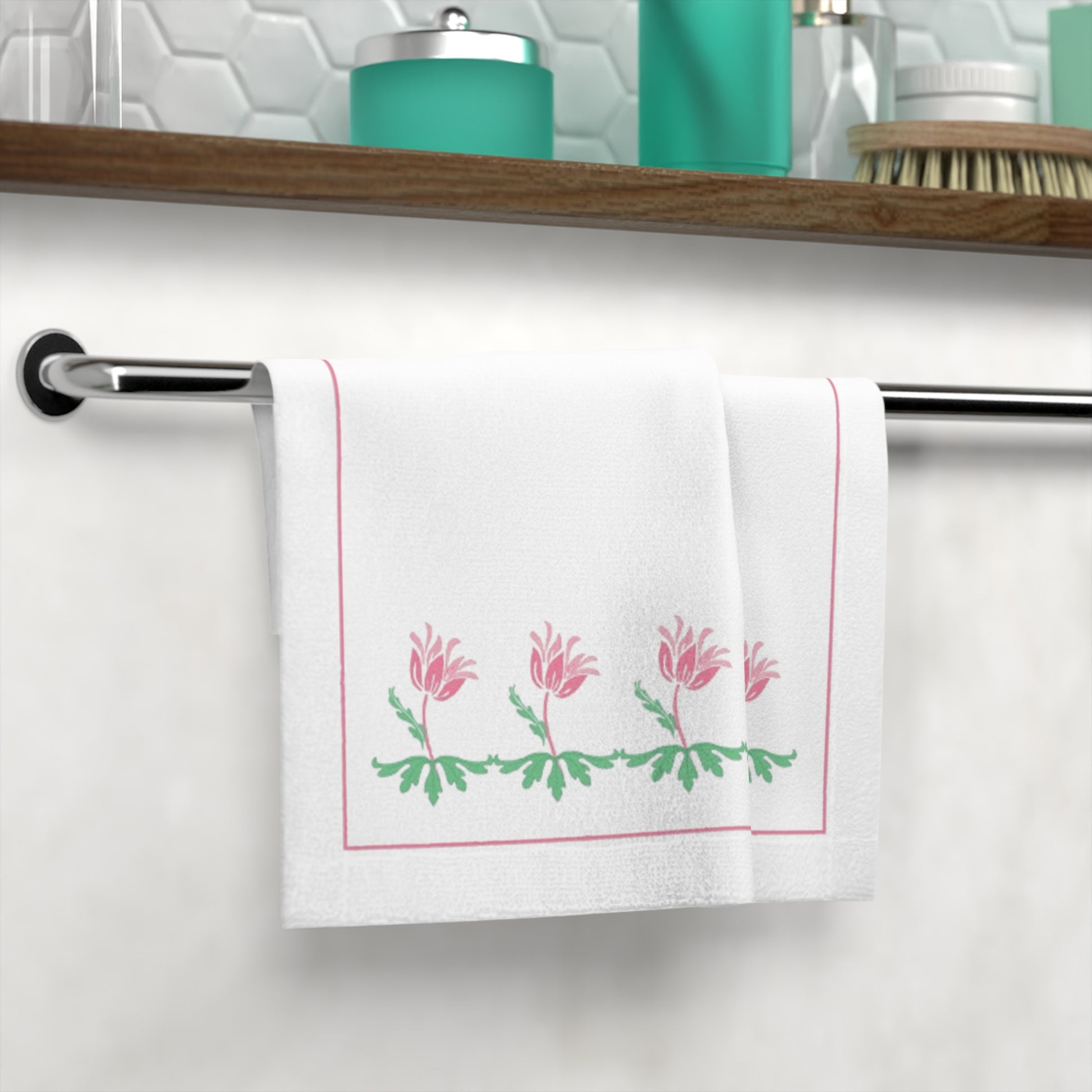 White towel with pink floral design hanging on a towel rack in a bathroom.