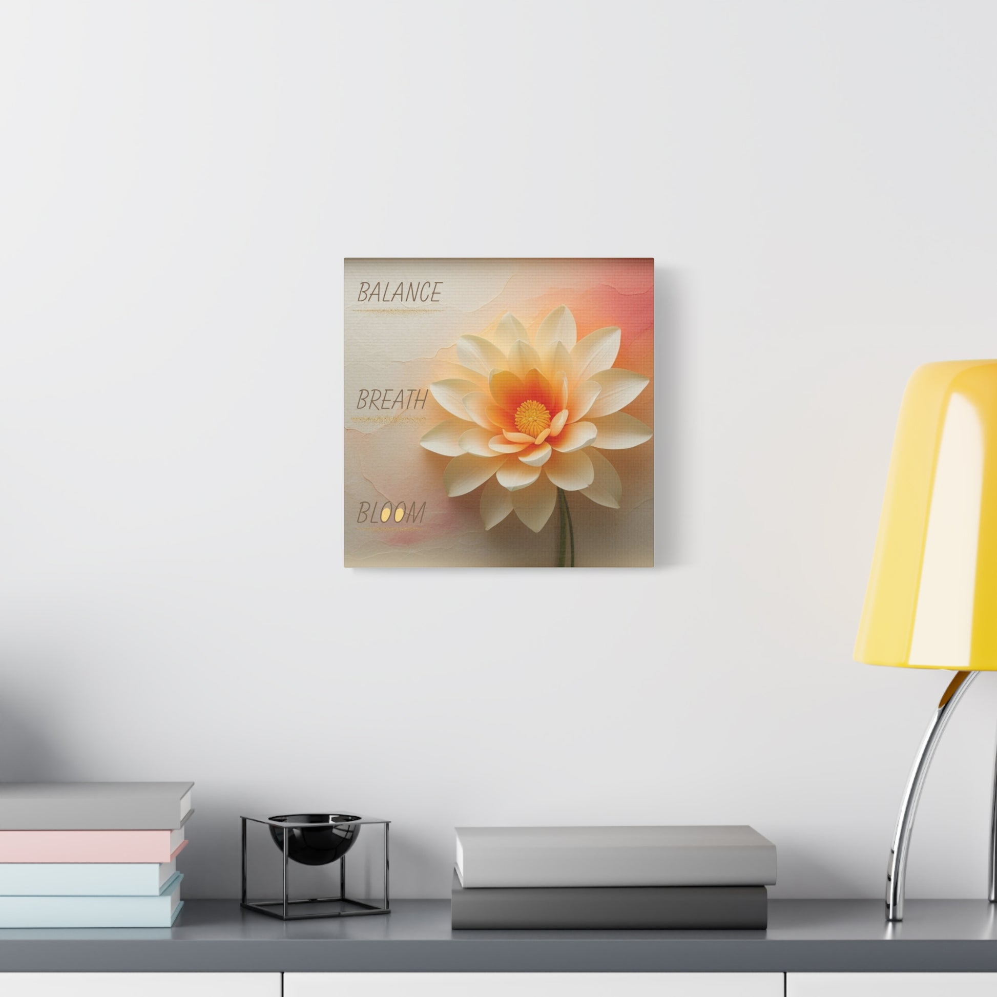 Decorative wall art of a flower on a white wall above a table with a lamp and books.