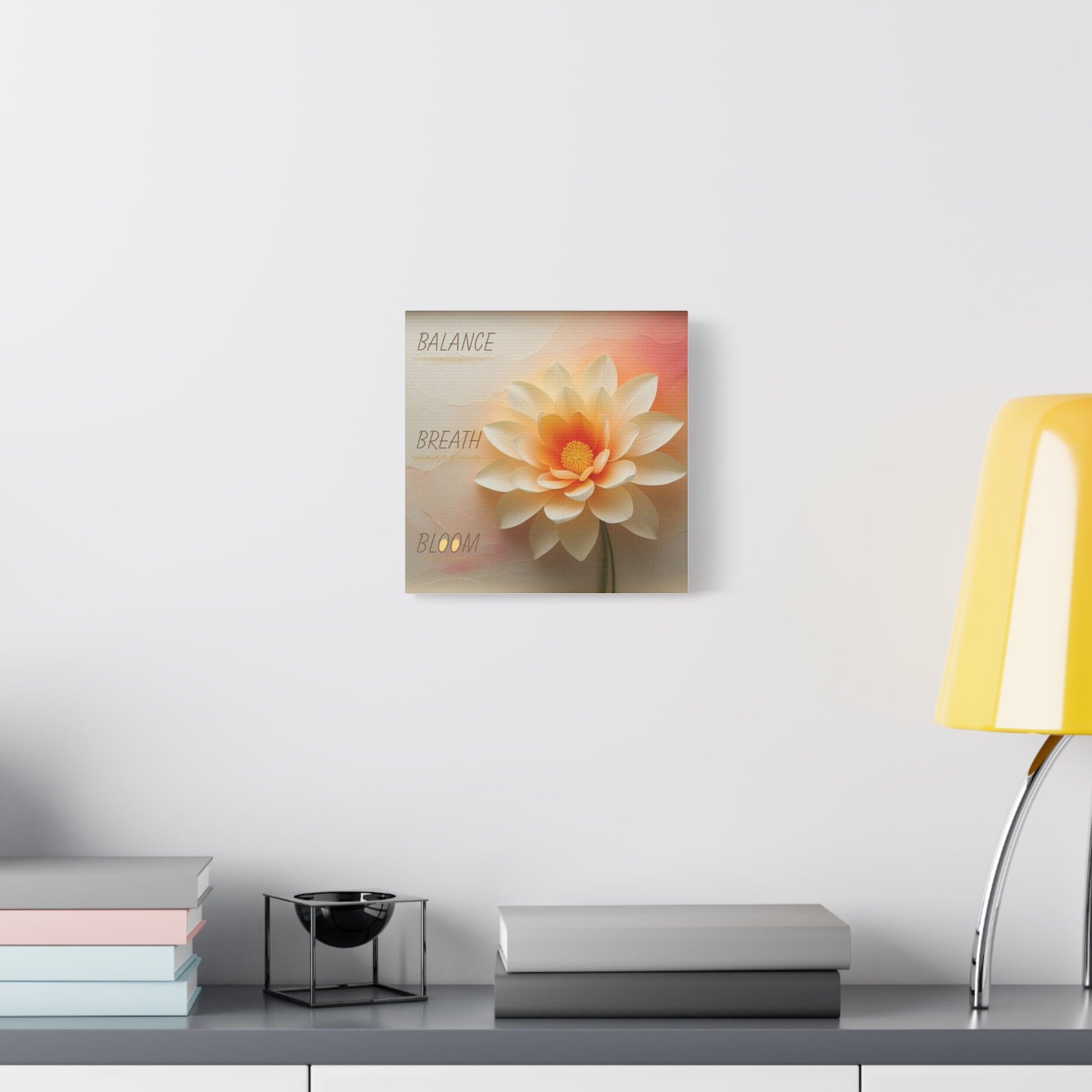 Decorative wall art of a flower on a white wall above a table with a lamp and books.