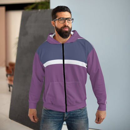A man wearing a purple and navy blue colorblock zip-up hoodie with a white chest stripe, paired with blue jeans, standing in an indoor setting.