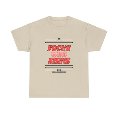 A sand unisex heavy cotton tee with the text 'FOCUS GRIND SHINE' printed on the front.