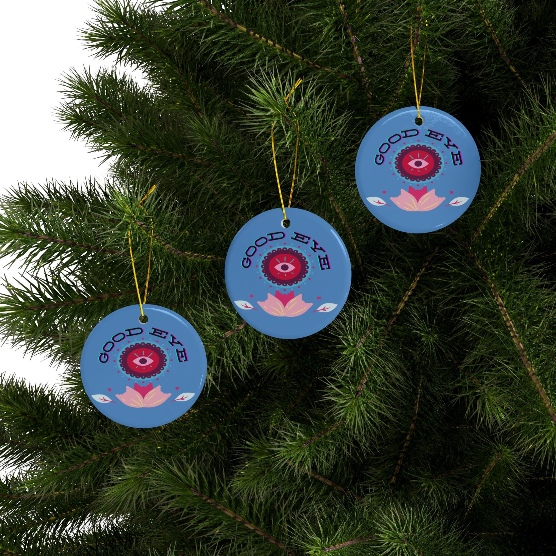 Blue decorative ornaments with red eye design on a green Christmas tree.