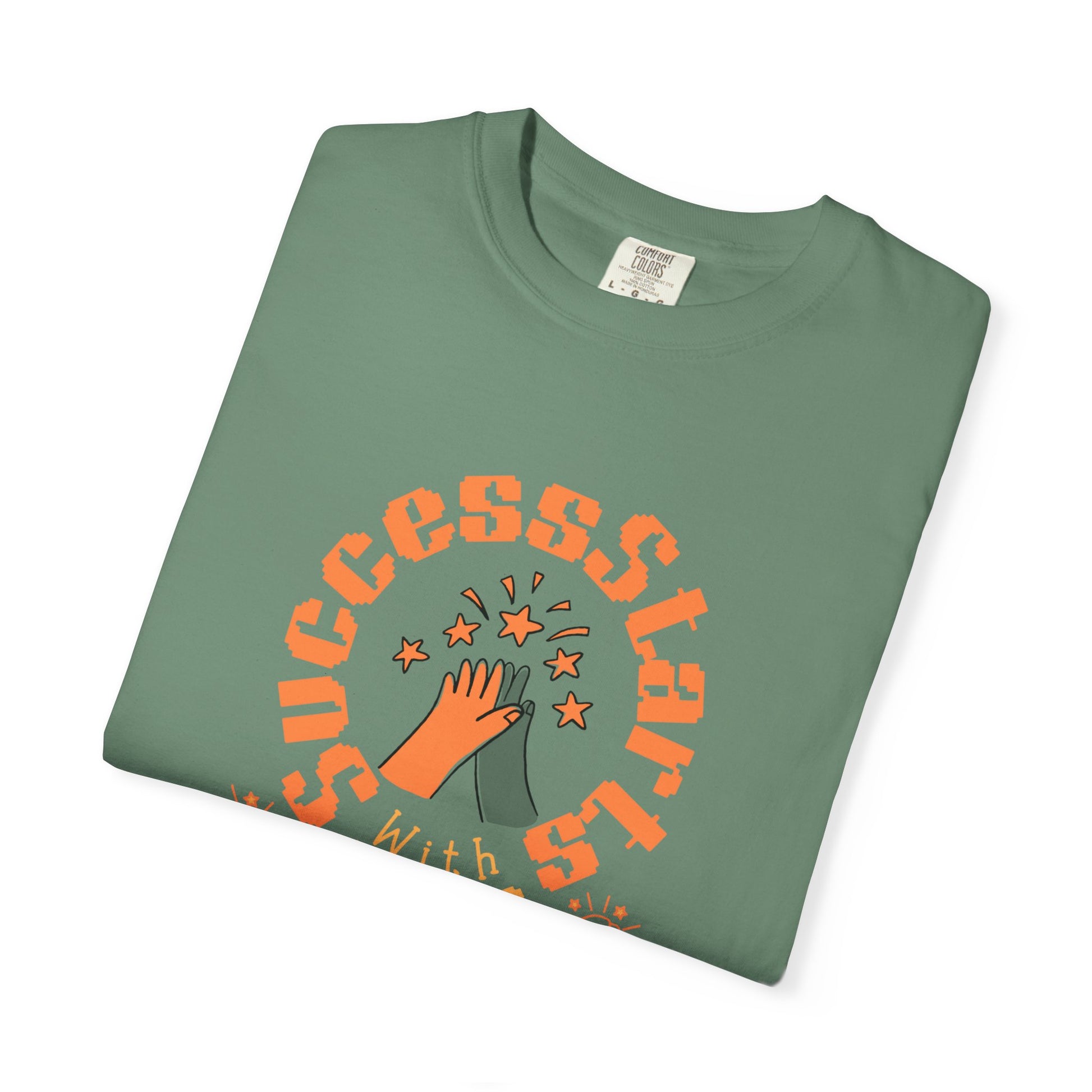 Folded green t-shirt with orange graphic and text on a white background