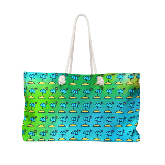 A multicolored weekender tote bag with a geometric pattern featuring an umbrella design, with a blue, green, and yellow color scheme, and white rope handles.