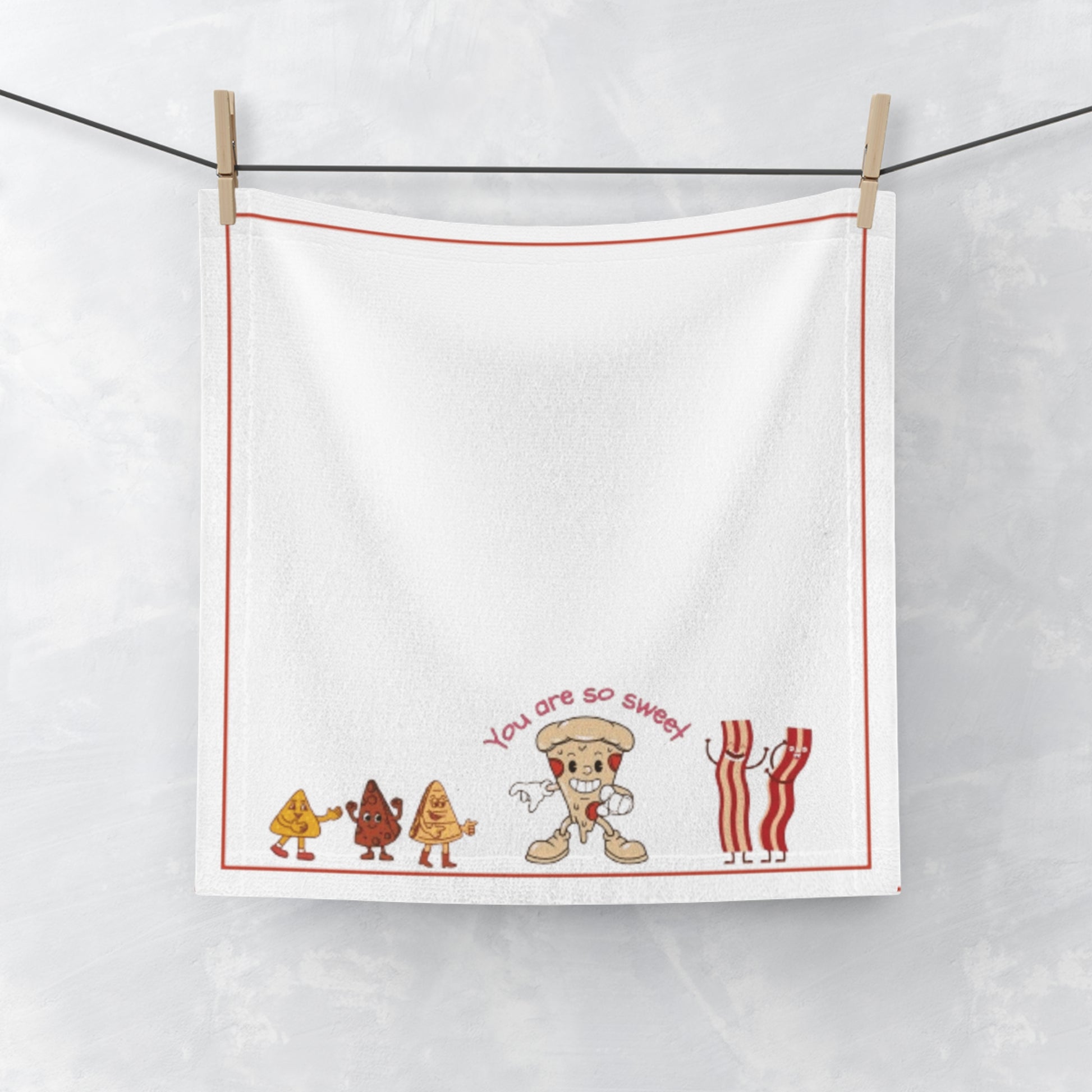 White towel with cartoon food characters and text hanging on a line.