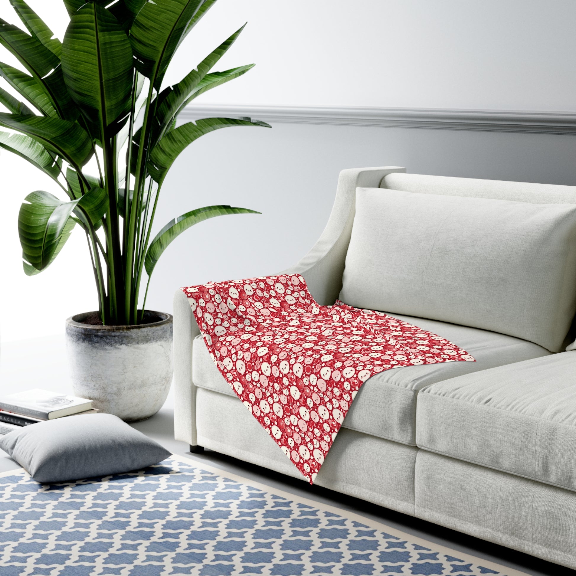 Red floral blanket on a gray sofa with a plant in the background.